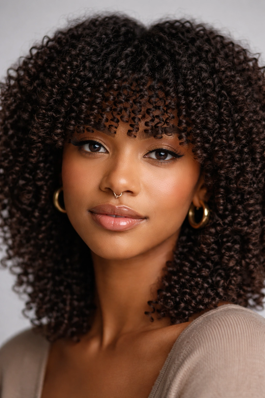 Close-up of blunt curve bangs on tight coils creating a defined forehead frame