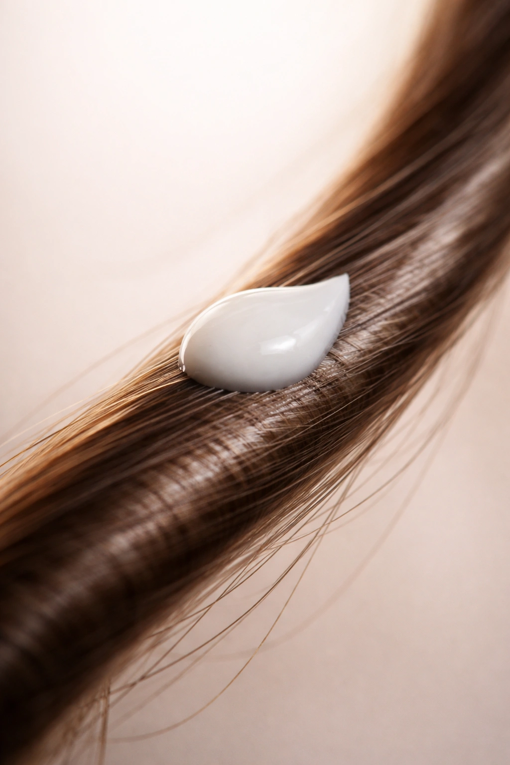 Hair strand with a tiny drop of body lotion on it, isolated.