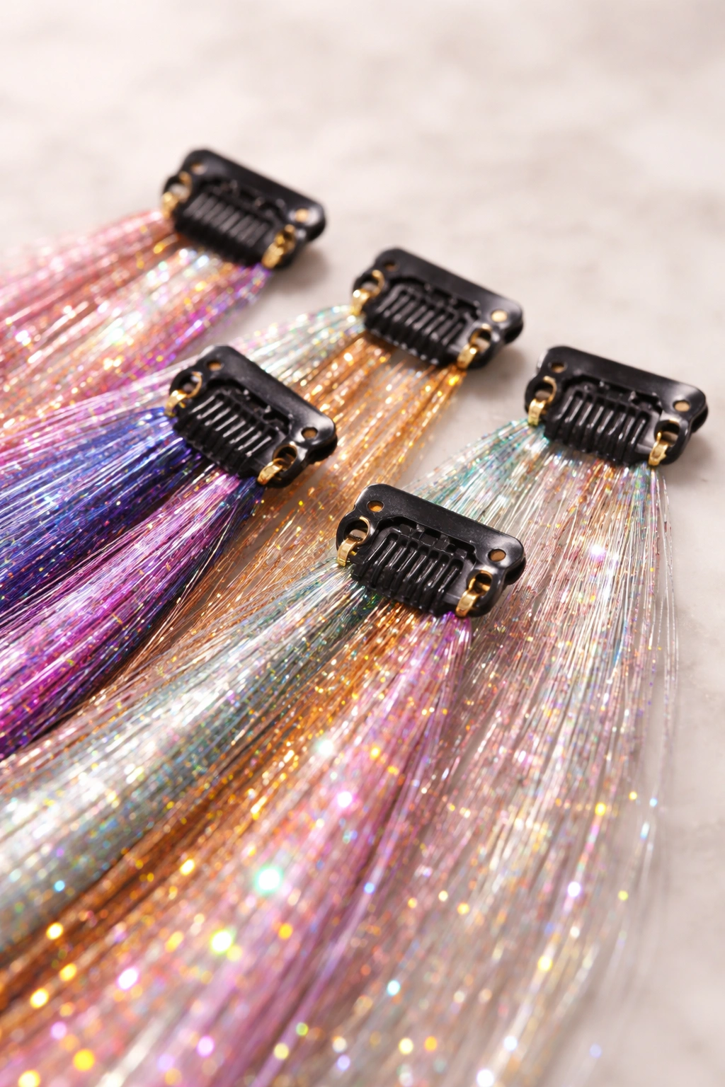 Close-up of plastic clips attached to hair tinsel strands on a neutral background.