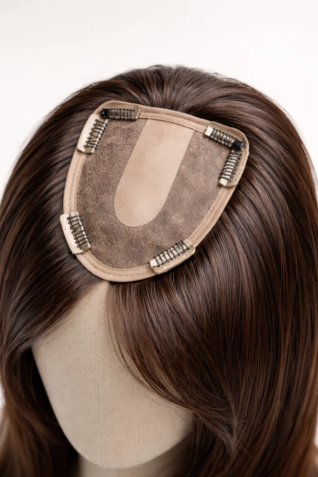 Clip-in hair topper with silicone clips on its base displayed on a head form