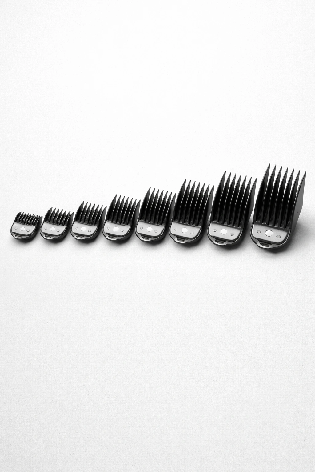 Row of clipper guards in varying lengths on a clean surface, no labels.