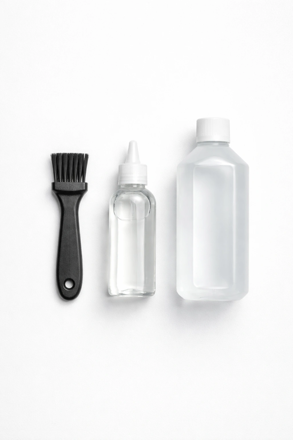 Flat lay of clipper cleaning kit including brush, oil, and alcohol