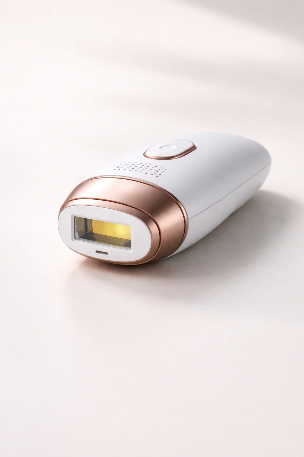 Handheld hair removal device on plain surface with soft shadows.