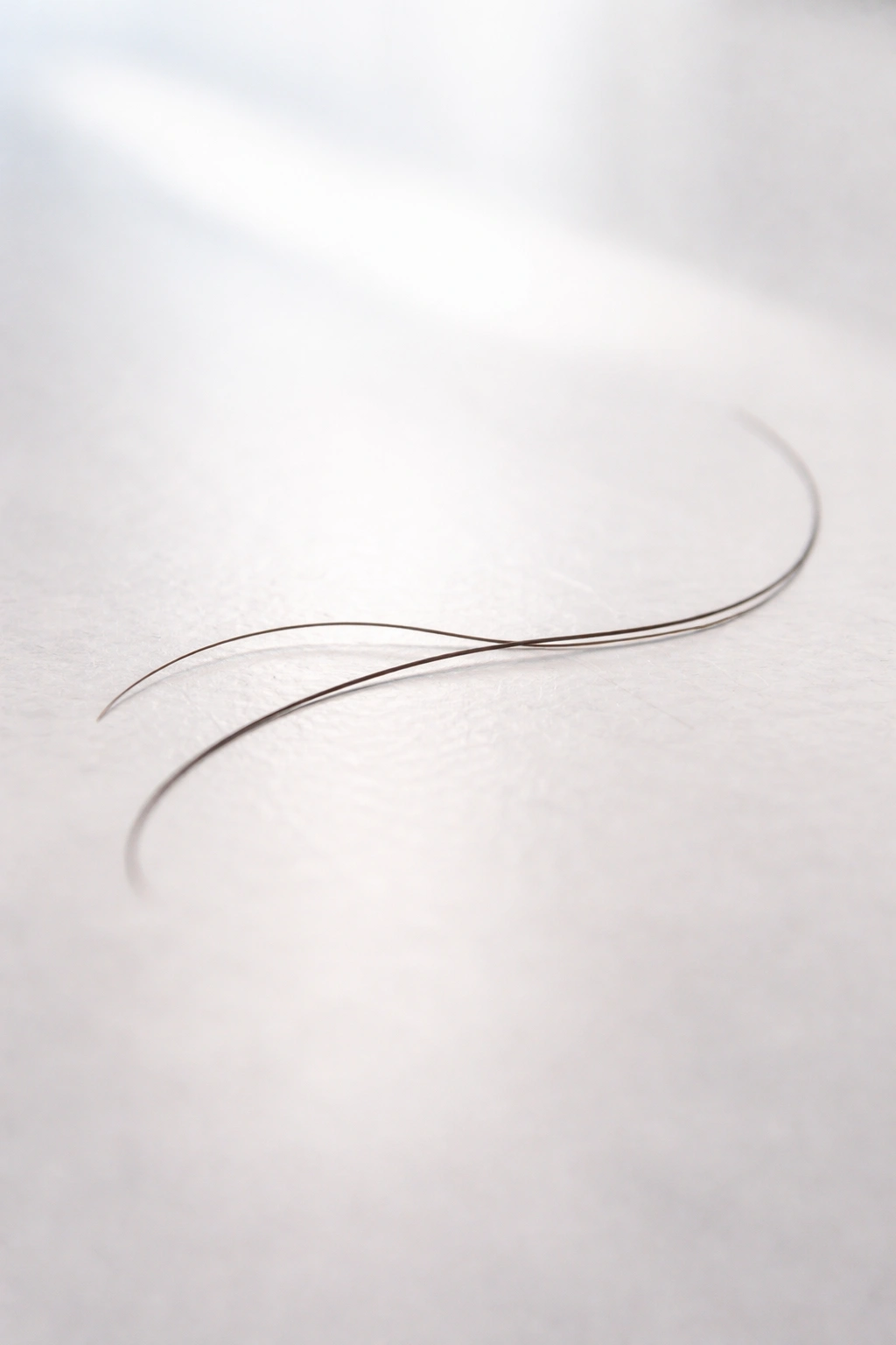Single hair strand on minimalist surface for final thoughts