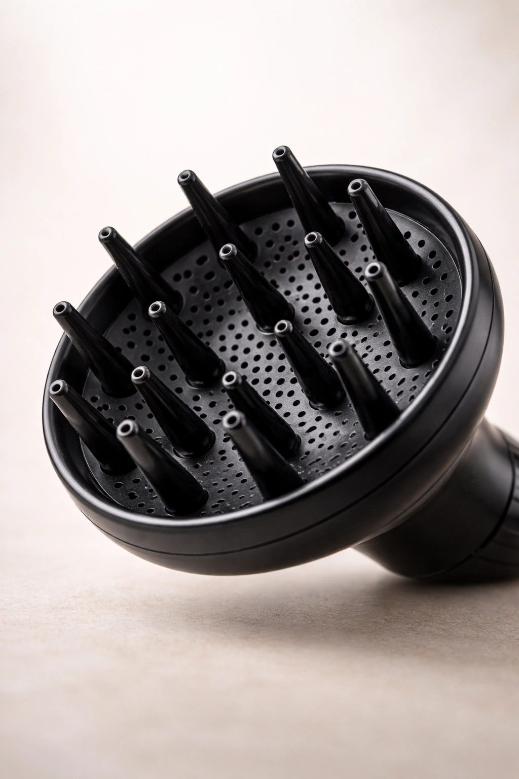 Close-up of a bowl-shaped hair dryer diffuser with prongs on a neutral background