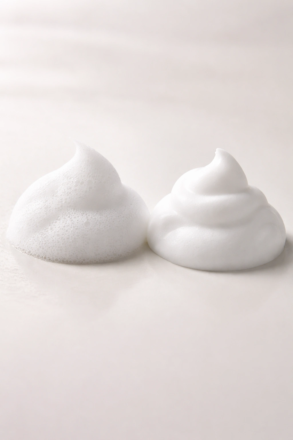 Two mousse foam blobs showing different textures on a plain surface
