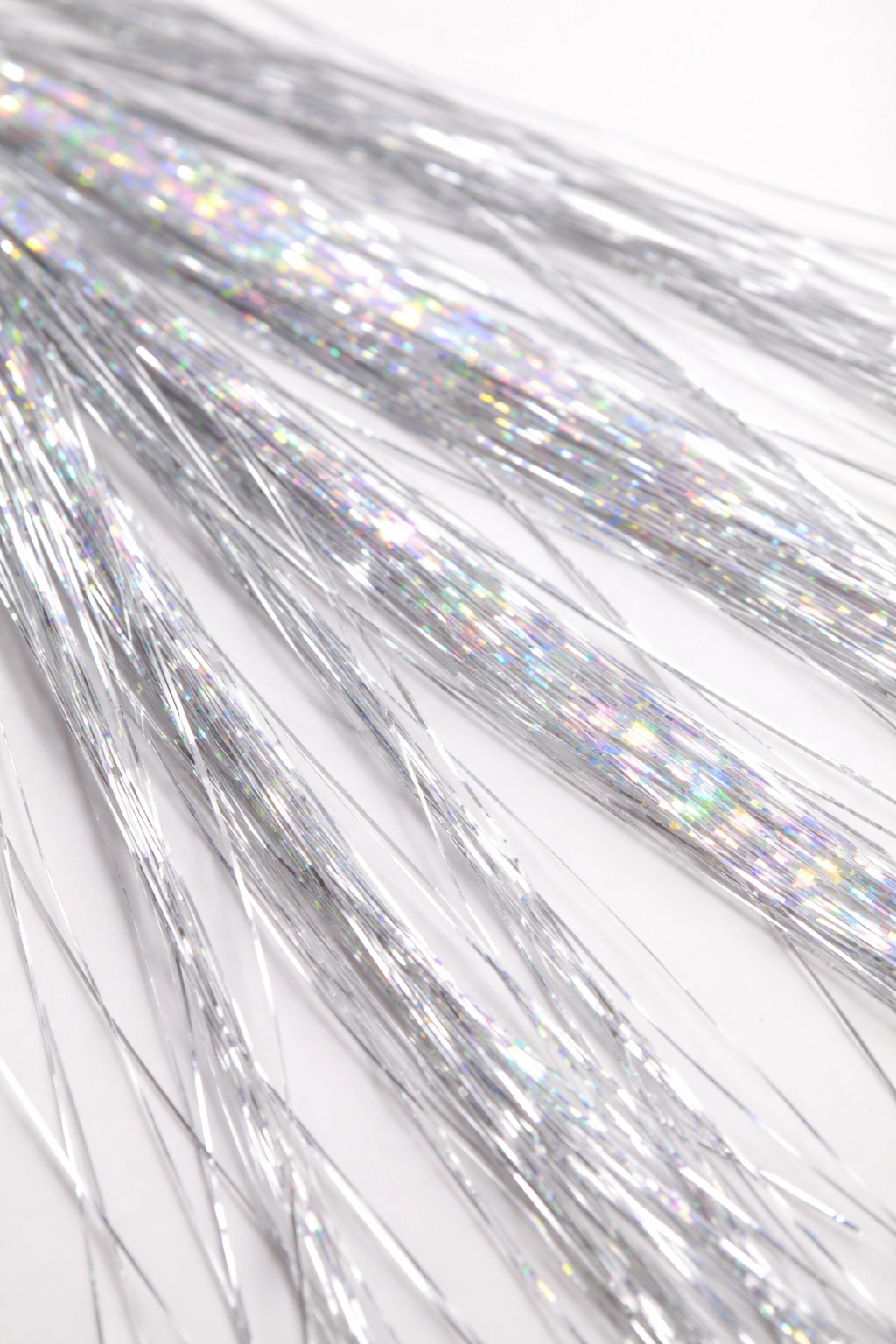 Close-up of metallic hair tinsel fibers in silver and holographic colors.