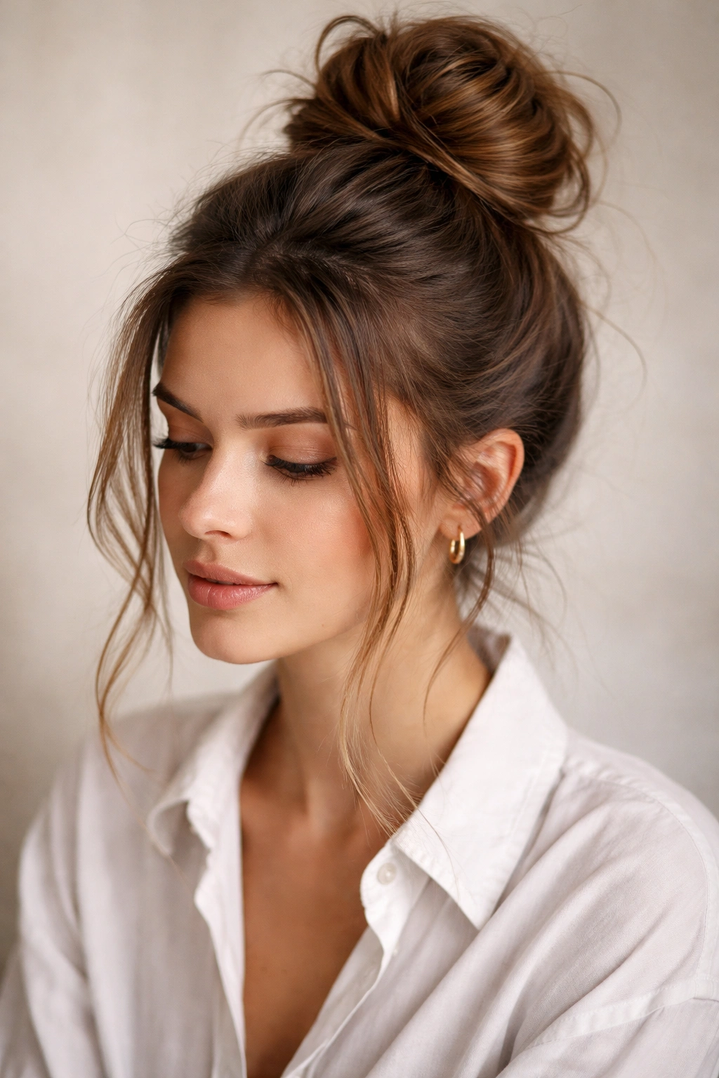 10 Hair Ideas For A Casual Shirt And Jeans Outfit 1 Close-up of a textured, messy high bun with face-framing strands.