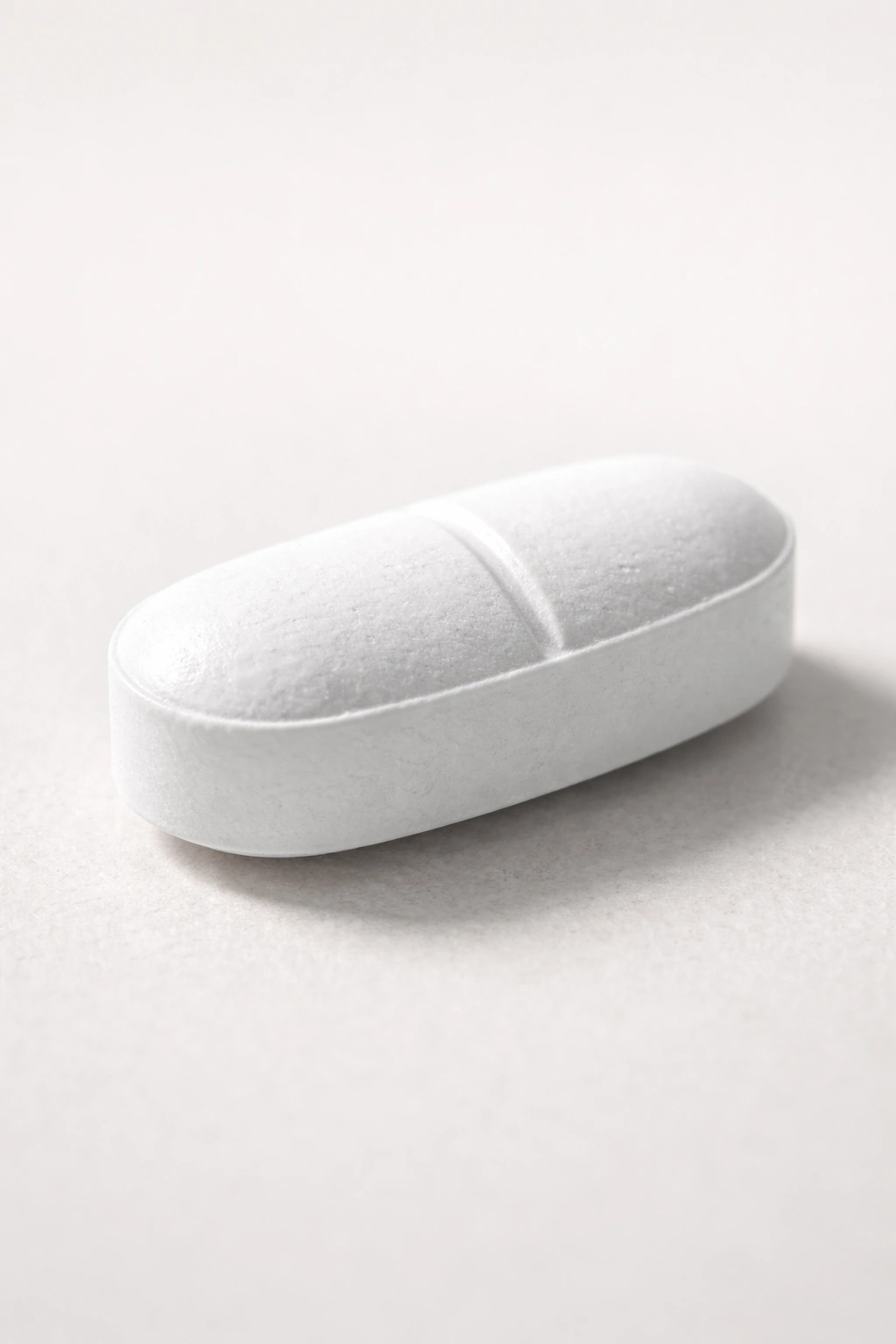 Close-up of a single magnesium tablet on a neutral background