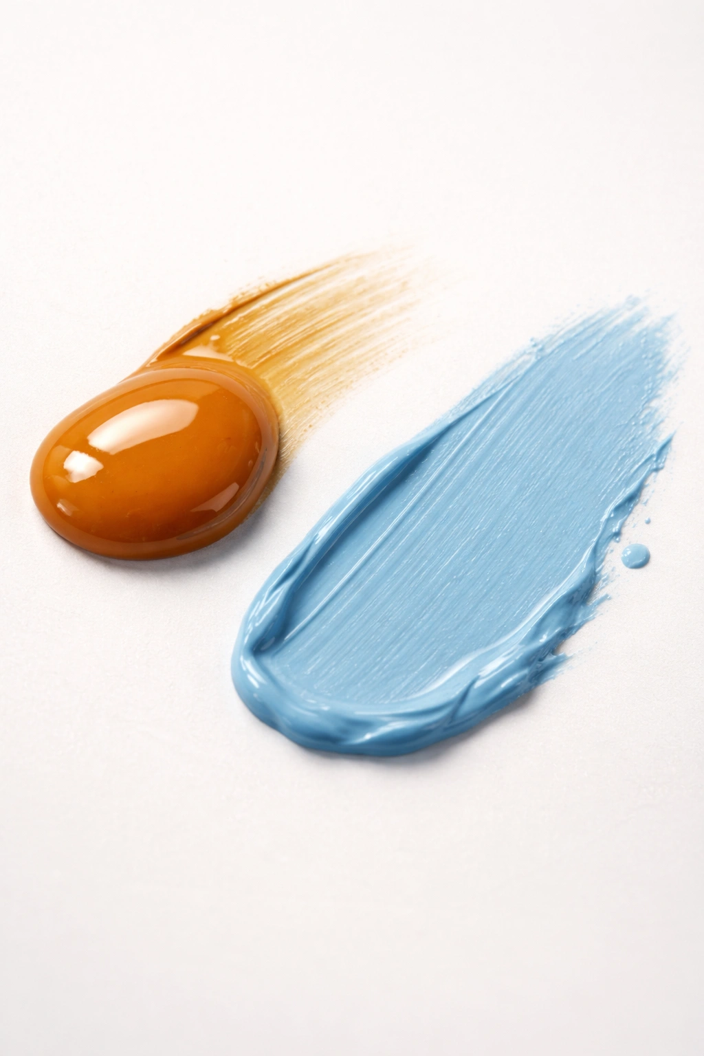 Close-up of glossy oil-based paint droplet and matte water-based paint smear on a neutral surface