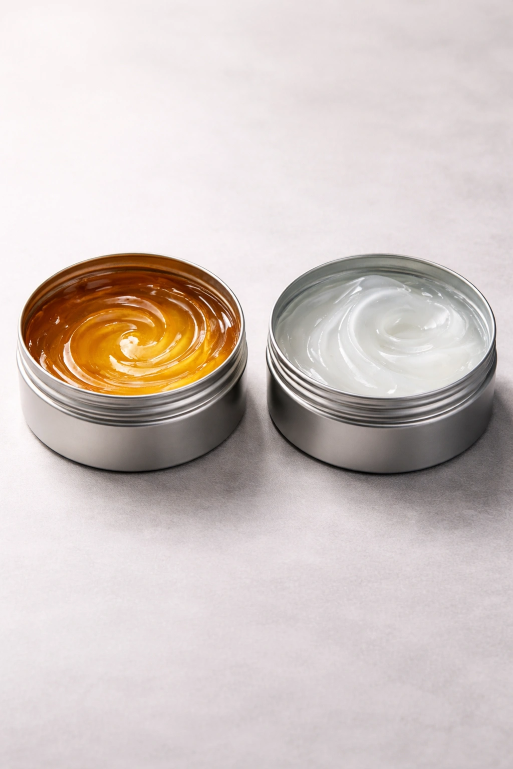 Two unmarked pomade tins on a clean surface showing different formulas
