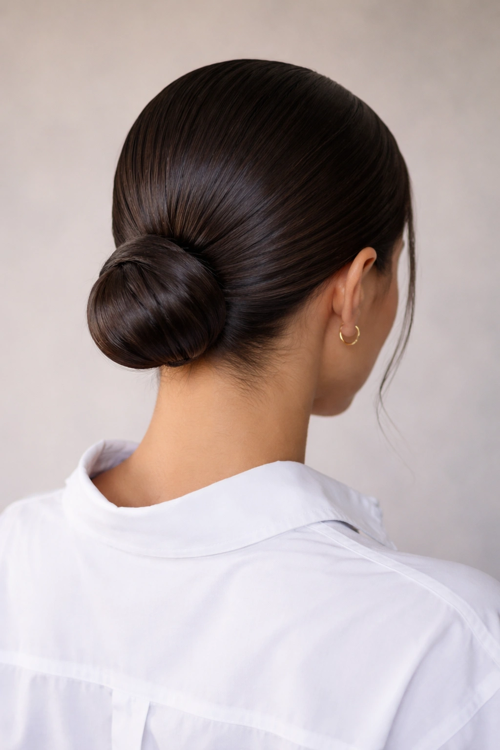 Back view of a sleek, glossy low bun at the nape